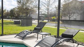 A poolside area with lounge chairs and a view of a residential neighborhood.
