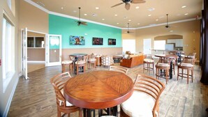 A spacious dining area with multiple wooden tables and chairs, ceiling fans, and recessed lighting. - Amazing 4Bd Screened Pool Close to Disney 4572 (Kissimmee)