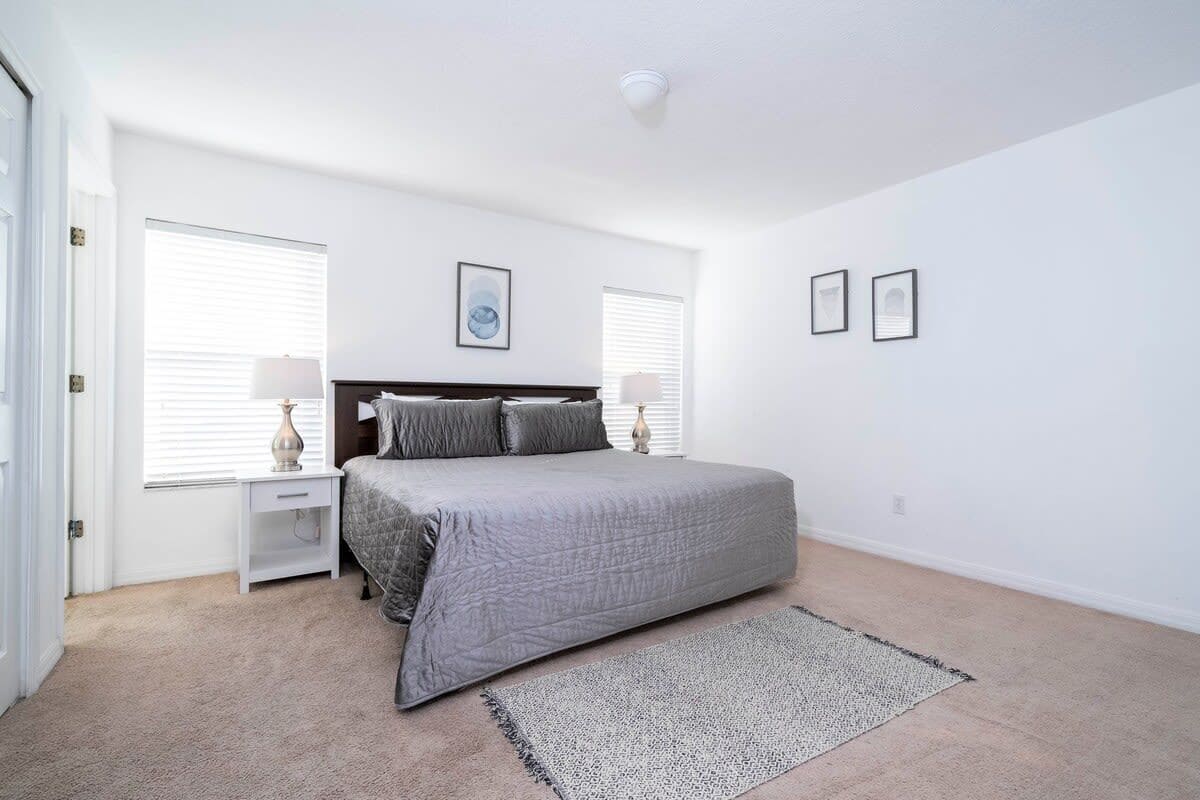 Une chambre à coucher avec un lit, des tables de chevet, un tapis et des tableaux encadrés accrochés au mur.