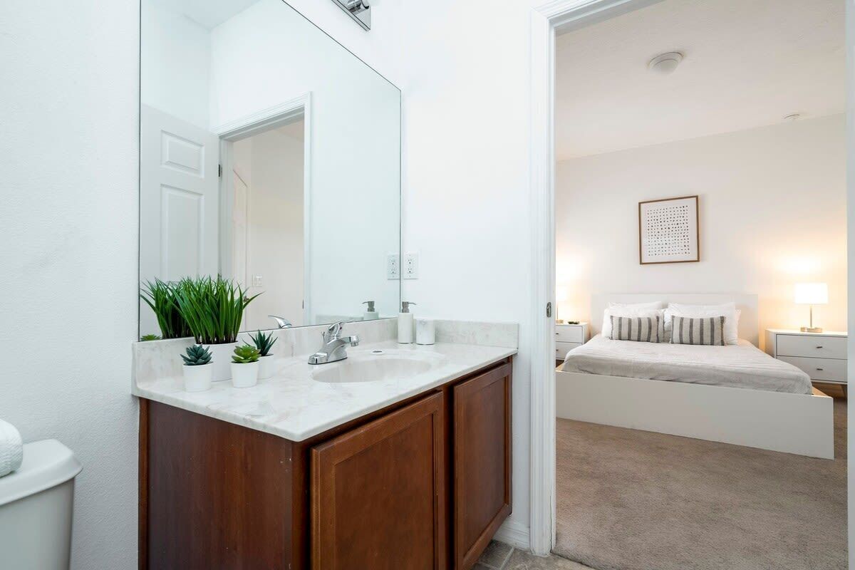 A modern bathroom with a white sink, wooden cabinets, and a large mirror.
