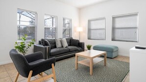 A modern living room with a sofa, armchair, coffee table, and a small side table. - Amazing 4Bd Screened Pool Close to Disney 4572 (Kissimmee)