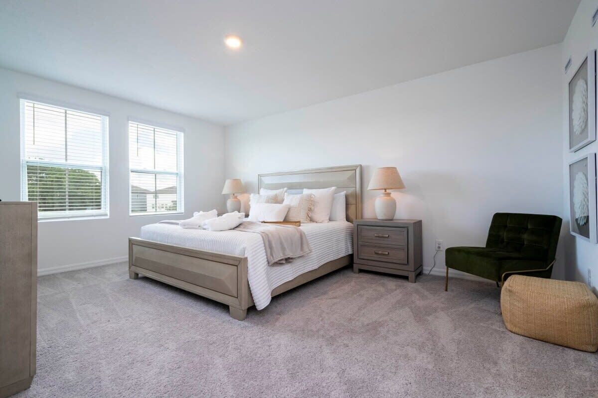 Une chambre à coucher comprenant un lit, des tables de chevet, une chaise et une commode.