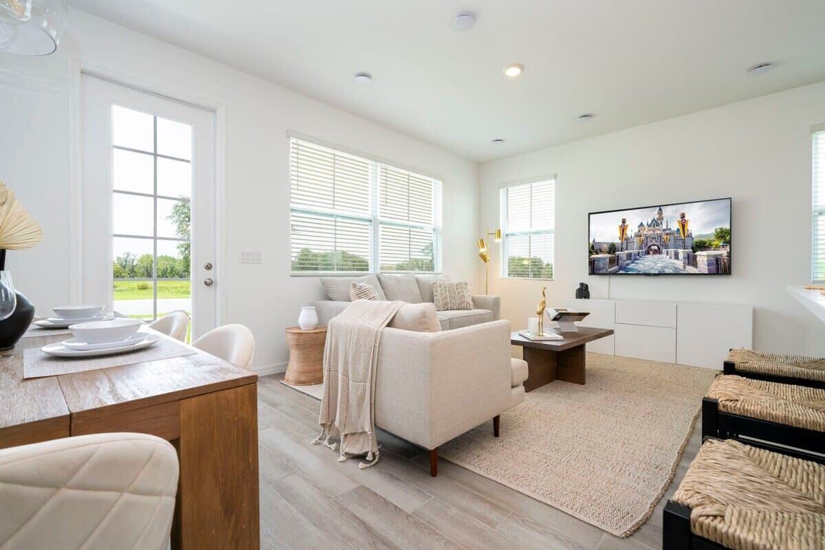 A spacious living room with a sofa, coffee table, and a television mounted on the wall.