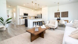 A modern kitchen with white cabinets, a central island, and pendant lighting. - Casa Serene 3Bd near Disney @Festival Resort 963 (Davenport)