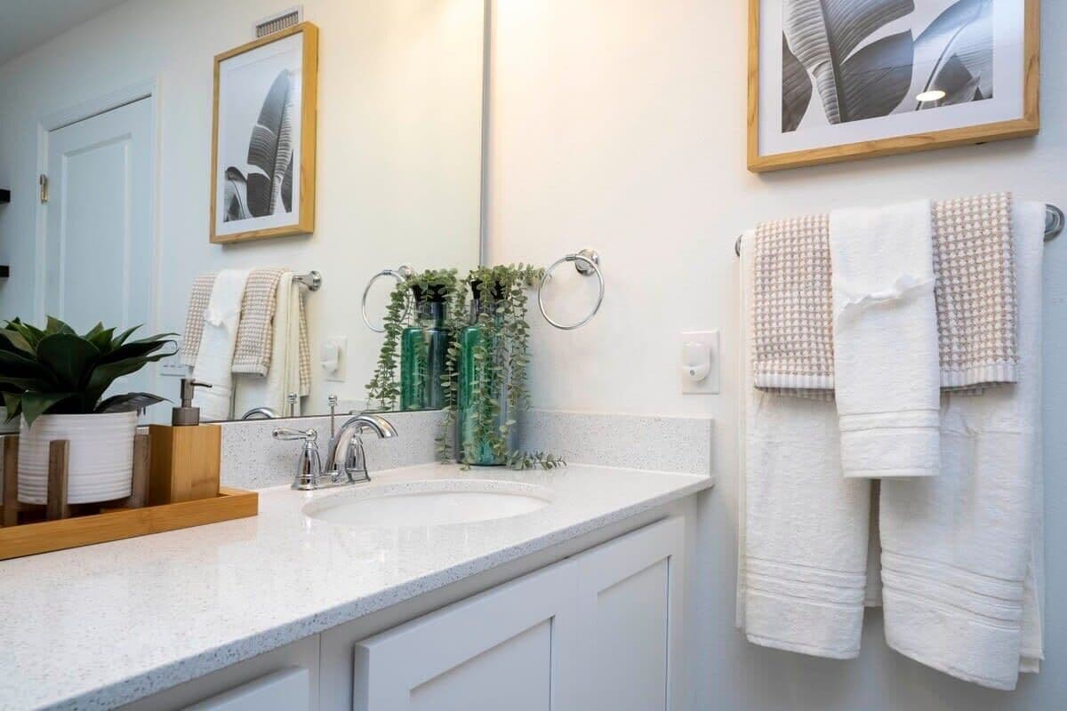 Une salle de bain moderne avec un lavabo blanc, deux tableaux encadrés et des serviettes sur un porte-serviettes.