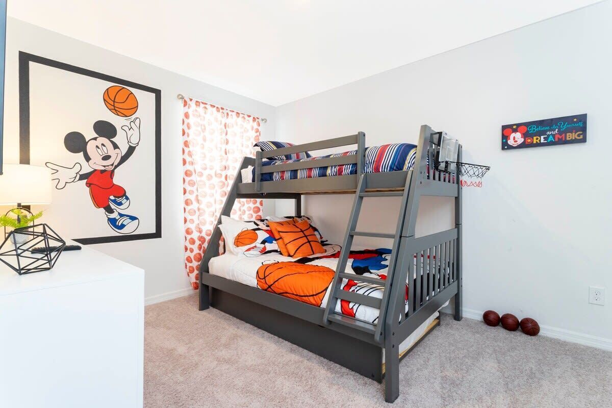 A bunk bed with a basketball theme, a framed Mickey Mouse picture, and a motivational sign on the wall.