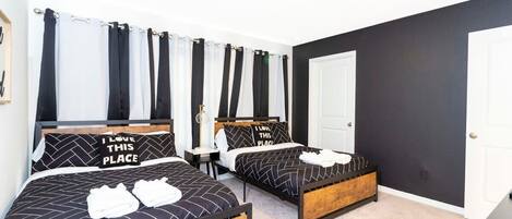 A bedroom with two beds, each with black and white bedding, and a wooden headboard.