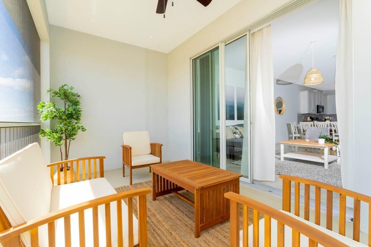 A balcony with a wooden table, two chairs, and a potted plant.