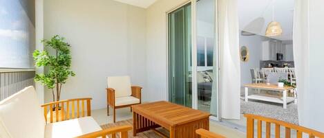 A balcony with a wooden table, two chairs, and a potted plant.