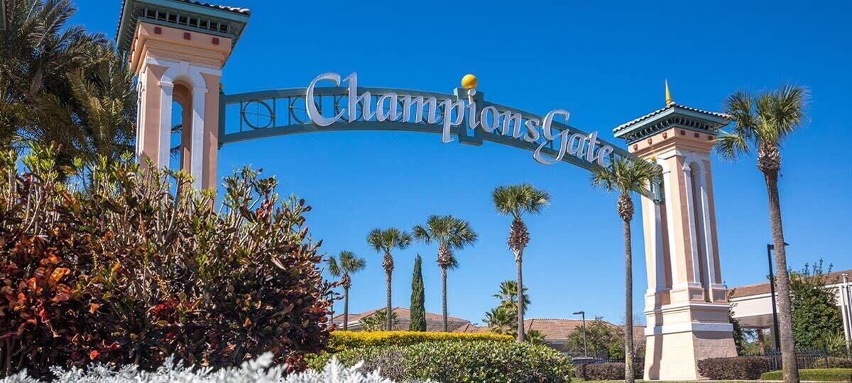 A sign reading "ChampionsGate" with palm trees and a clear blue sky in the background.