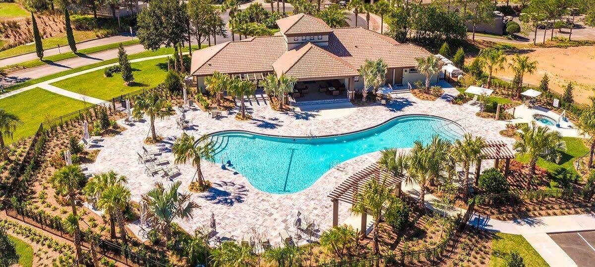 Luchtbeeld van een resort met een groot zwembad, loungegedeeltes en een gebouw met een betegeld dak.