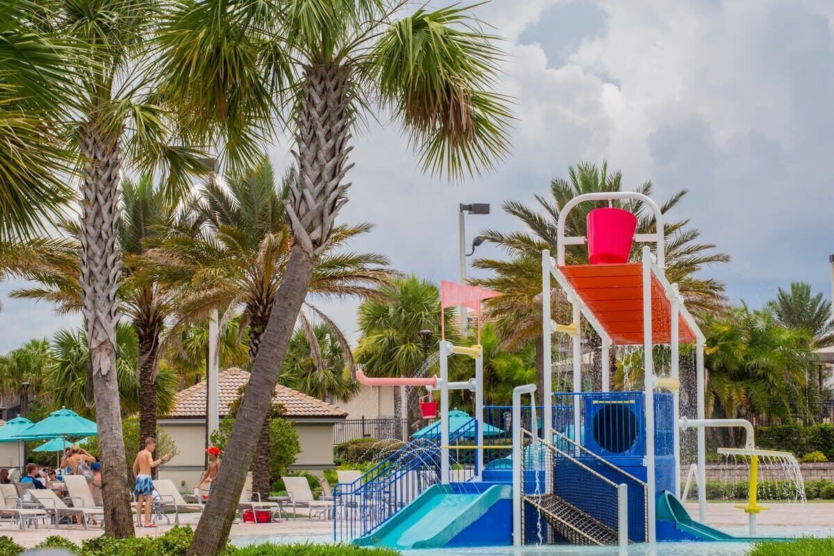 Ein Wasserpark mit Rutschen und Poolbereich, umgeben von Palmen und Liegestühlen.