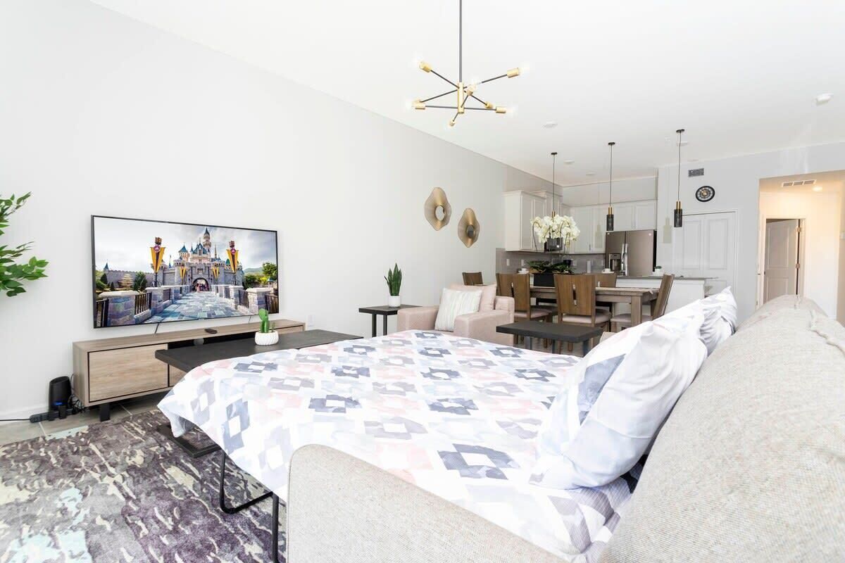 Et moderne hotelværelse med en stor seng, et fjernsyn, et spiseområde og et køkken.