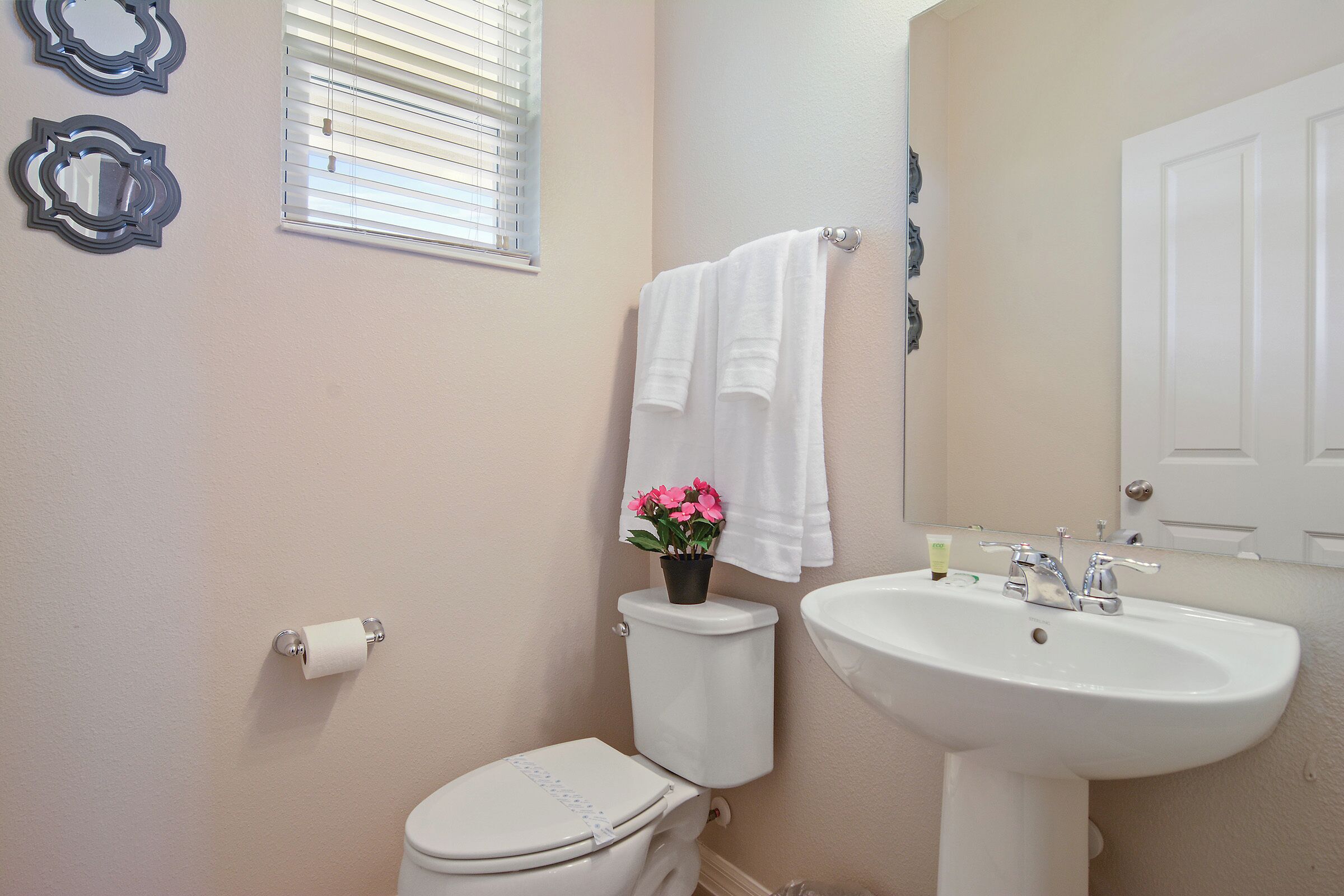 A bathroom with a toilet, sink, and a window with blinds.