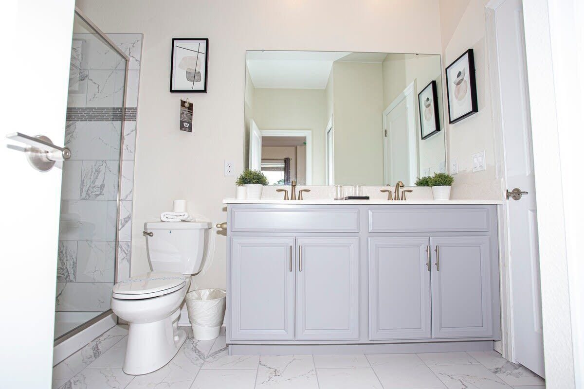 Een badkamer met toilet, douche en wastafel met spiegel.