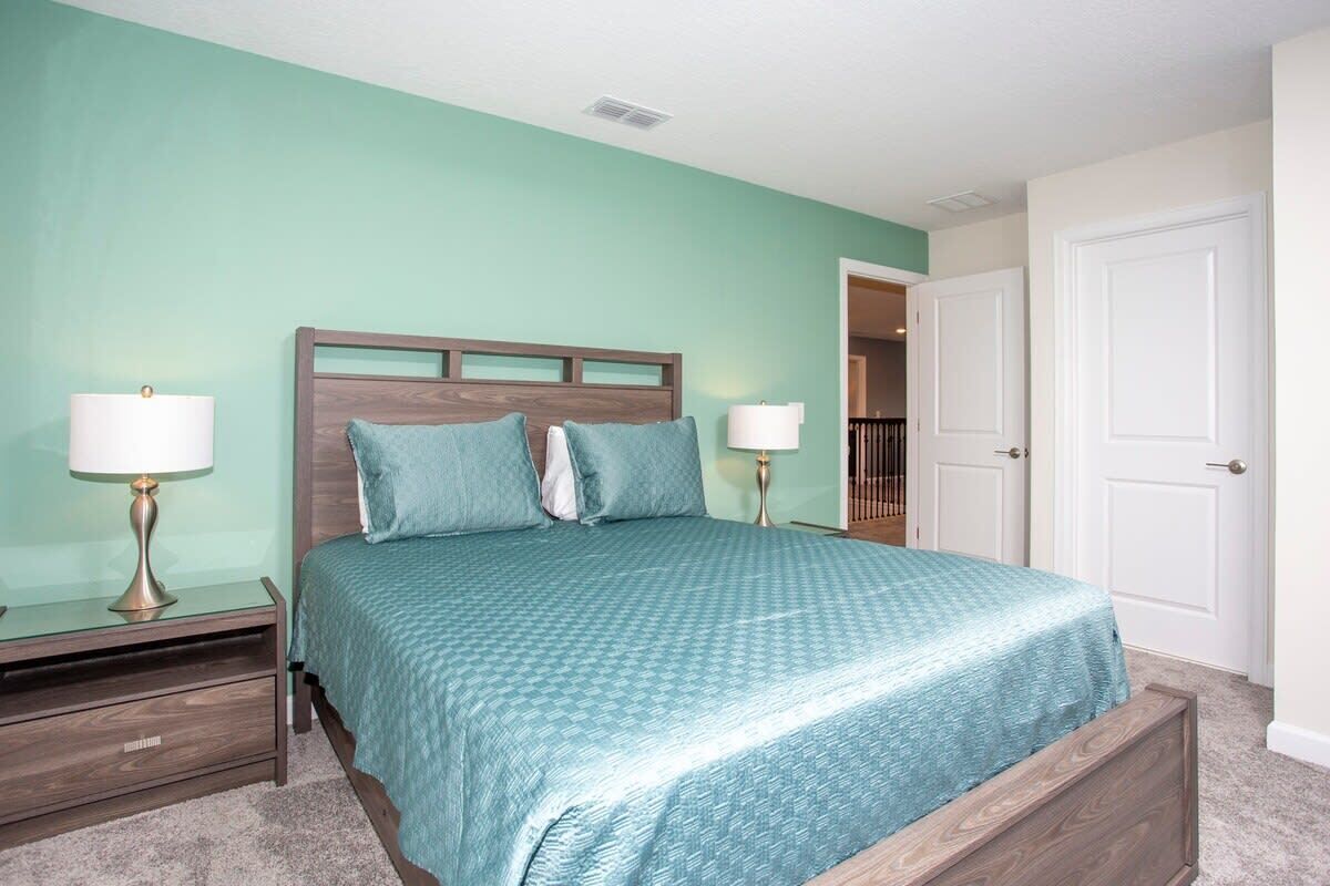 A bedroom with a bed, nightstands, and a door.