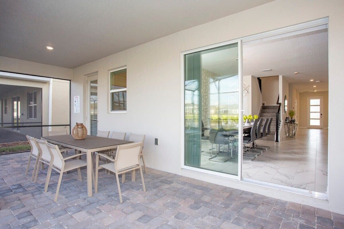 A modern interior with a dining area, a glass door leading to a balcony, and a staircase.