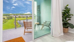 A balcony with a view of a green landscape and buildings, a wicker chair, a small round table, and a potted plant. - Gorgeous 2Bd Apto Close to Disney @ Storey Lake 404 3191 (Kissimmee)