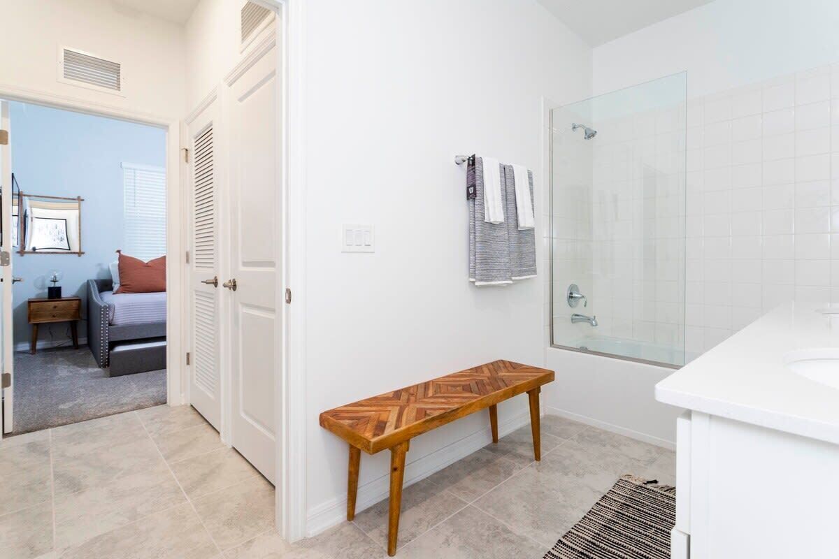 A bathroom with a shower, a bench, and a toilet.
