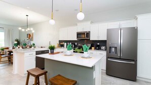 A modern kitchen with white cabinets, stainless steel appliances, and a central island with stools. - Gorgeous 2Bd Apto Close to Disney @ Storey Lake 404 3191 (Kissimmee)