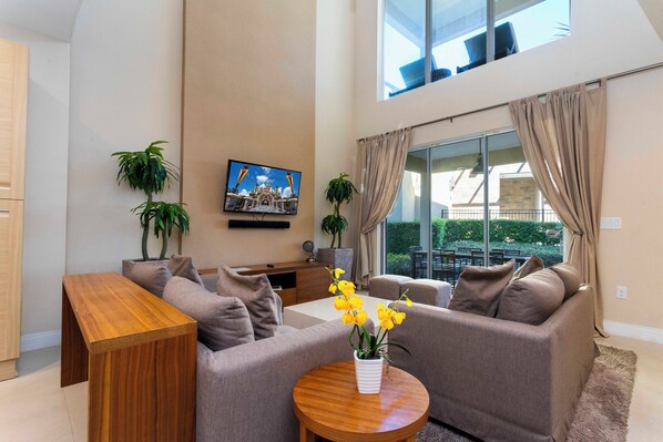 A modern living room with a sofa set, a wooden coffee table, and a TV mounted on the wall.