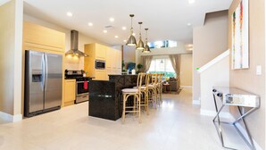 Una cocina moderna con una isla central, electrodomésticos de acero inoxidable y sillas de madera.