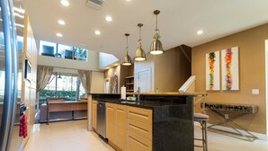 Una cocina moderna con una isla central, armarios de madera e iluminación colgante.