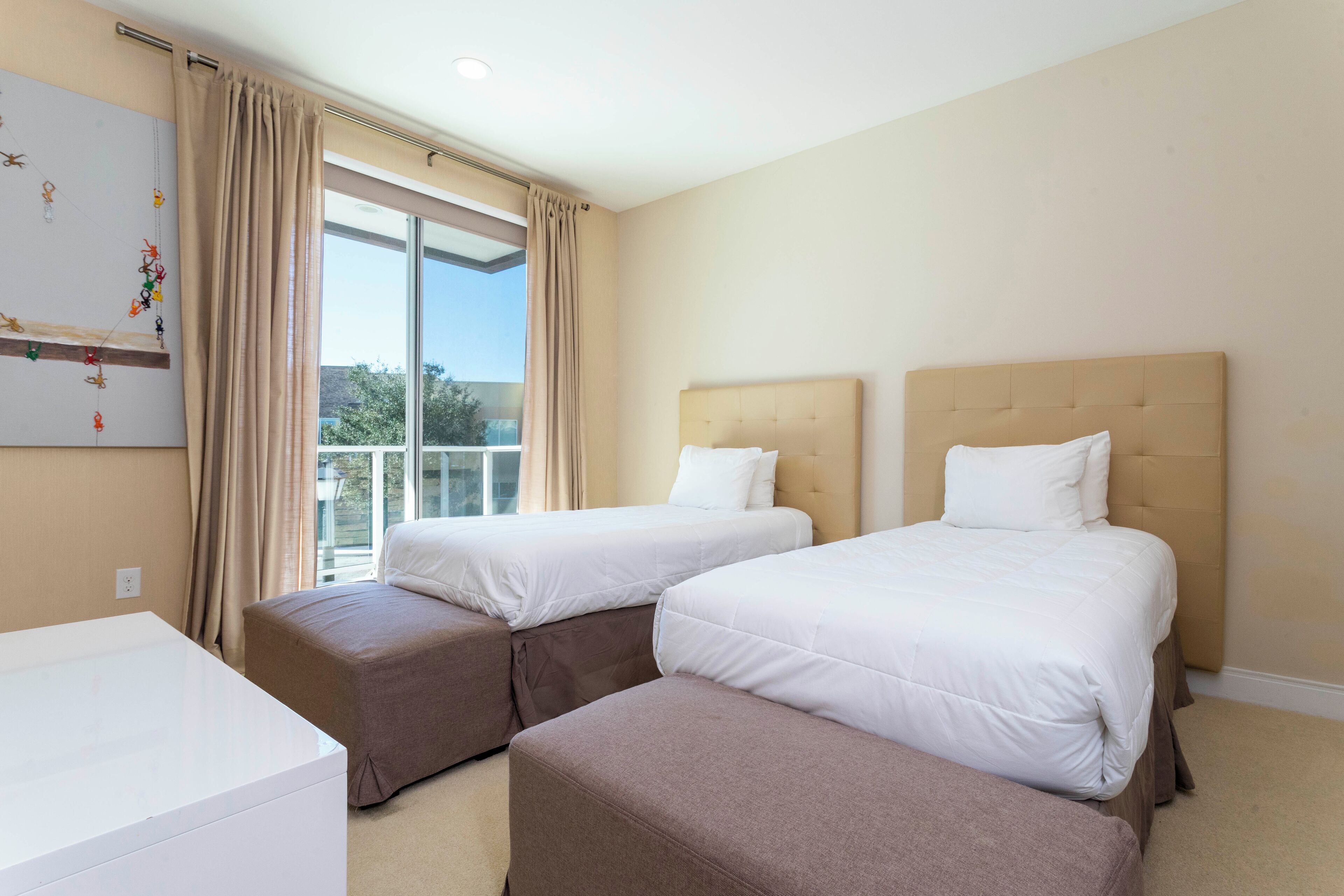 Ein Hotelzimmer mit zwei Betten, einem Schreibtisch und einem großen Fenster mit Vorhängen.