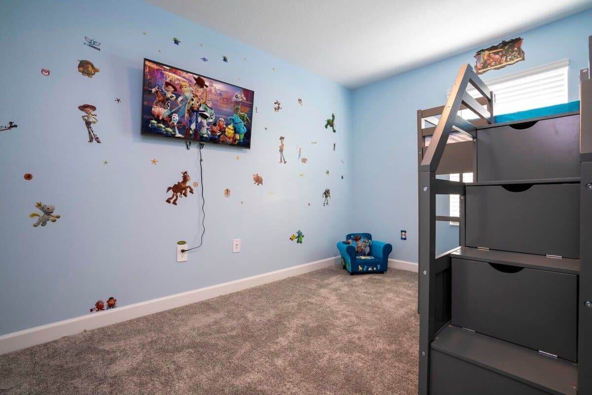 A room with a bunk bed, a TV mounted on the wall, and various wall stickers.