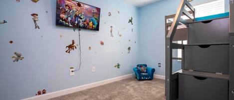 A room with a bunk bed, a TV mounted on the wall, and various wall stickers.