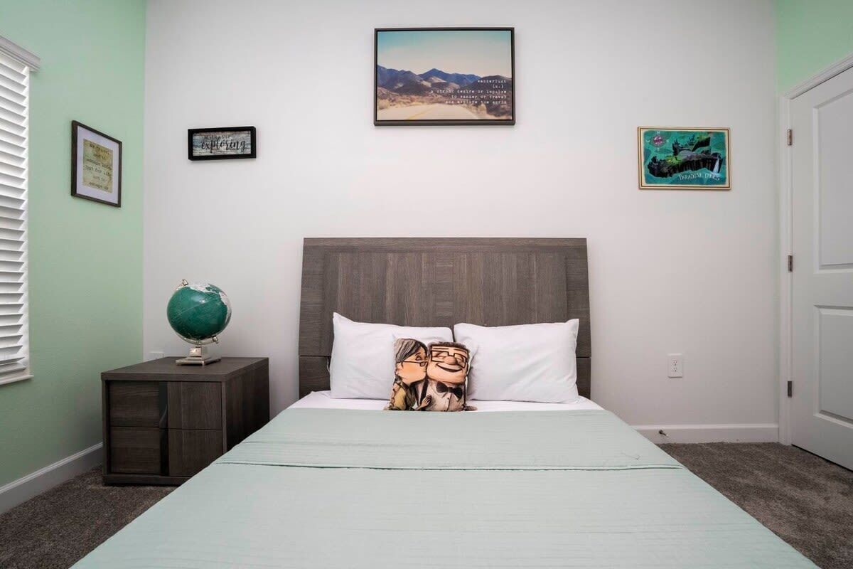 A bedroom with a bed, a nightstand with a globe, and two framed pictures on the wall.