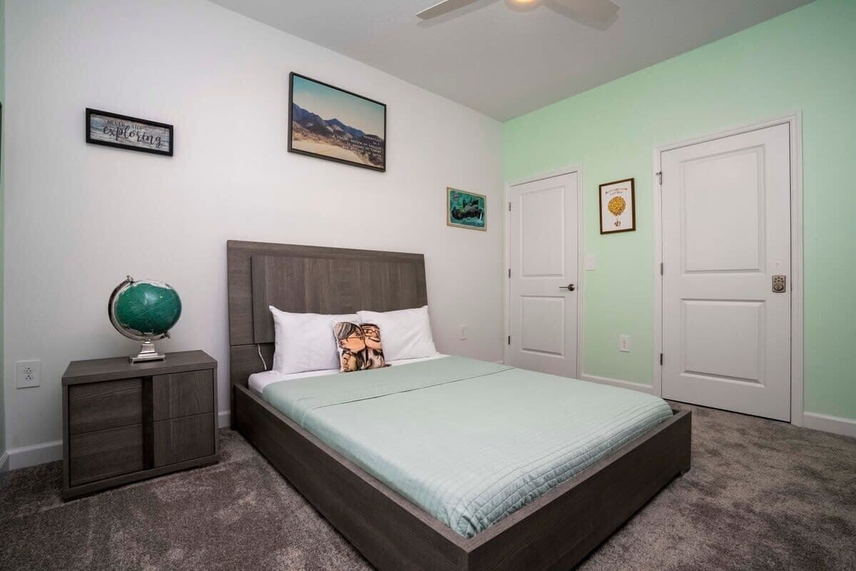 A bedroom with a bed, a nightstand, a globe, and two doors.