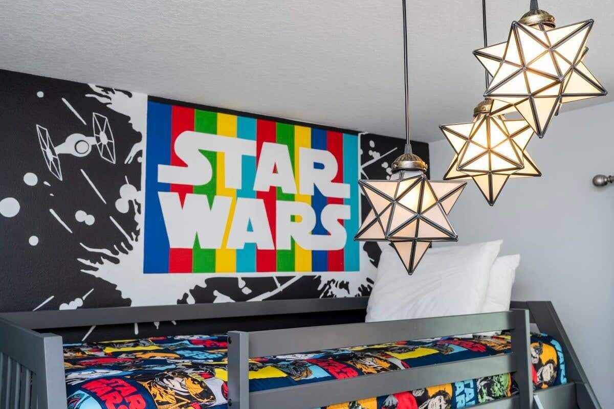 A Star Wars-themed bedroom with a bed, Star Wars posters, and geometric star-shaped lights.