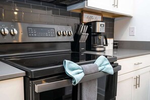 Enjoy cooking in this well-equipped kitchen with a stainless steel range hood, black stovetop, and convenient coffee machine.