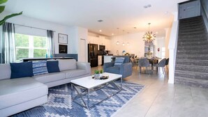 Un salon moderne comprenant un canapé, une table basse et un coin repas avec des chaises.