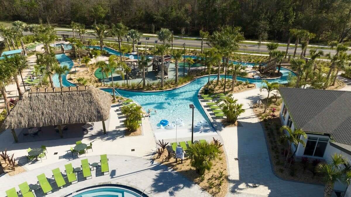 Un complejo turístico con varias piscinas, palmeras y zonas de descanso.