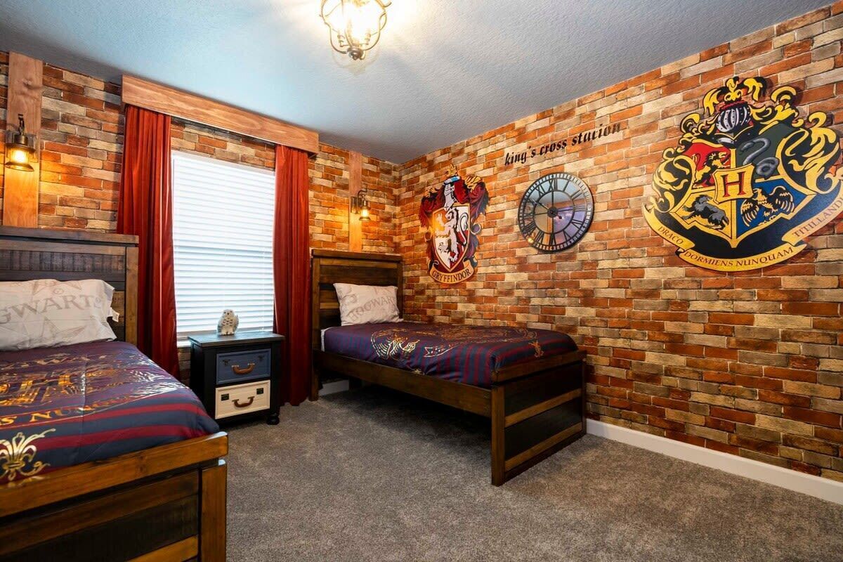 A bedroom with a brick wall, two beds, a nightstand, and a wall clock.