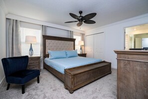 A bedroom with a large bed, a chair, a dresser, and a ceiling fan.