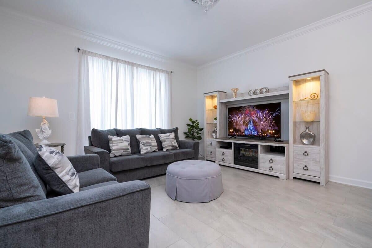 A modern living room with a grey sofa set, a television, and a white entertainment unit.
