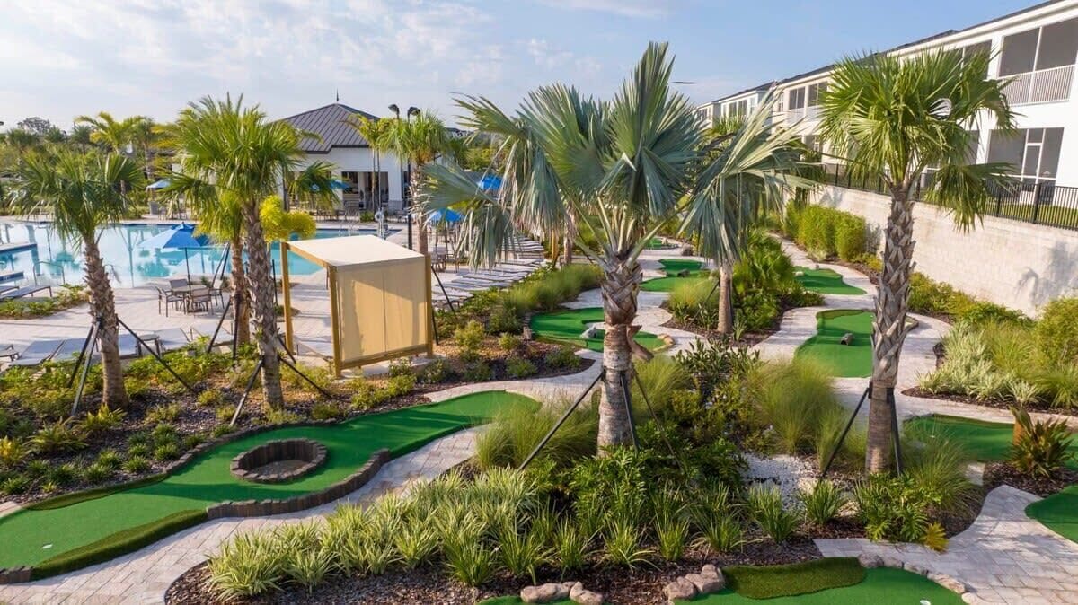 Ein Golfplatz mit Pool, Palmen und einem Gebäude im Hintergrund.