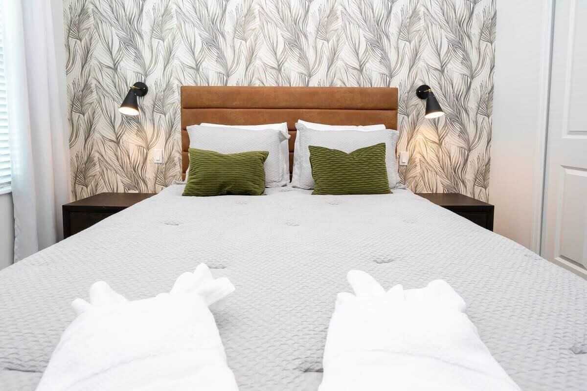 A bed with a white quilt, two green pillows, and a wooden headboard.