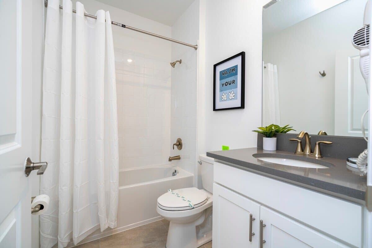 A modern bathroom with a bathtub, toilet, and vanity with a sink and mirror.