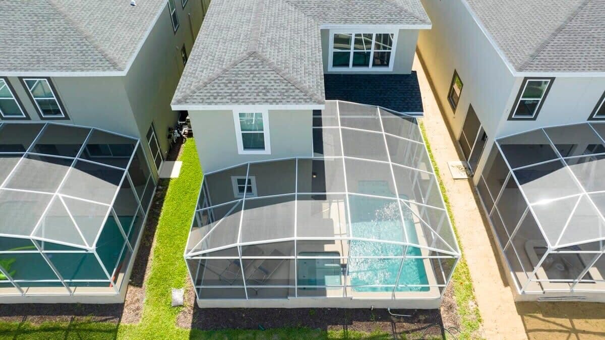 Um edifício residencial moderno com piscina, amplas janelas de vidro e um gramado bem cuidado.