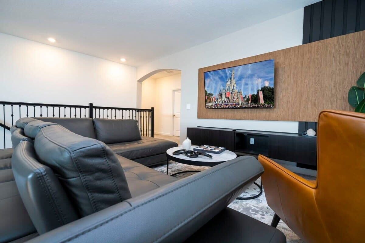 A modern living room with a grey sofa, a brown armchair, and a coffee table with a remote control.