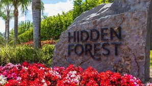 A large rock with the words "HIDDEN FOREST" engraved on it, surrounded by colorful flowers. - Marvelous 3Bd w/ Pool Near Disney at Serenity 1536 (Clermont)