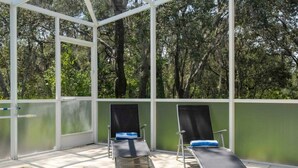 A covered outdoor area with a pool, two lounge chairs, and a view of trees. - Marvelous 3Bd w/ Pool Near Disney at Serenity 1536 (Clermont)