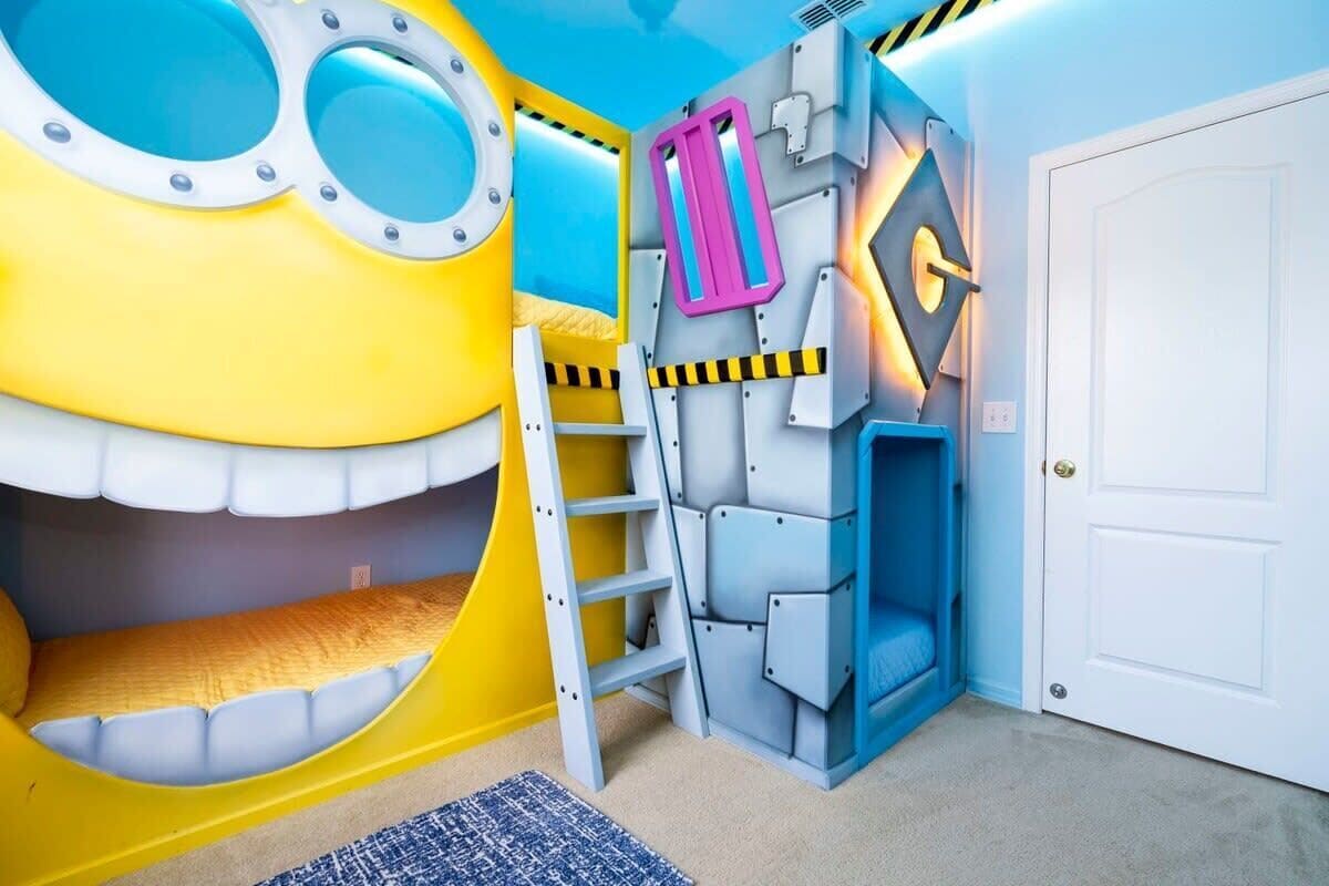 Une salle de jeux pour enfants avec un grand Minion gonflable, une échelle et une structure de jeu bleue.