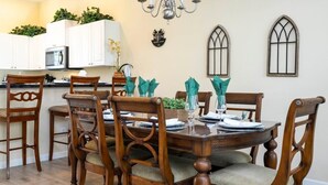 A dining area with a round wooden table, six chairs, and a chandelier. - Marvelous 4Bd Close to Disney w/ Pool at 313 Tuscan Hills (Davenport)