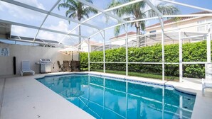 An indoor swimming pool with a glass ceiling, surrounded by greenery and a clear view of palm trees. - Marvelous 4Bd Close to Disney w/ Pool at 313 Tuscan Hills (Davenport)