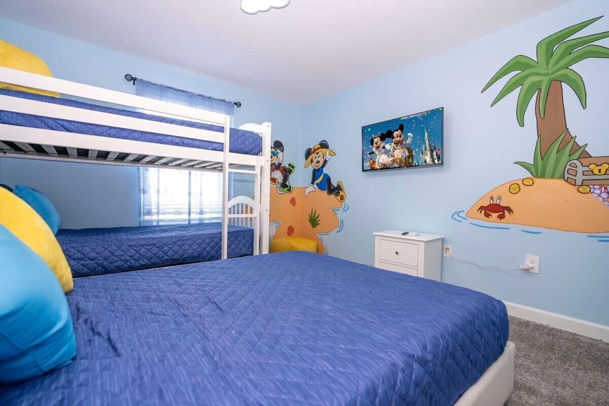 A child's bedroom with bunk beds, a mural of cartoon characters, and a small nightstand.